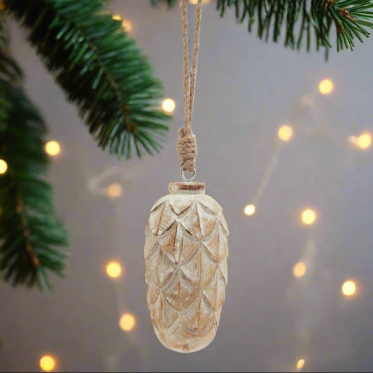 Decorative pinecone ornament with textured surface and twine string hanging from a Christmas Tree.