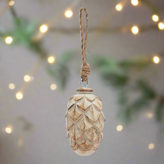 Beautiful intricately detailed pine cone hanging ornament in a white wash finish hanging in a festive setting.