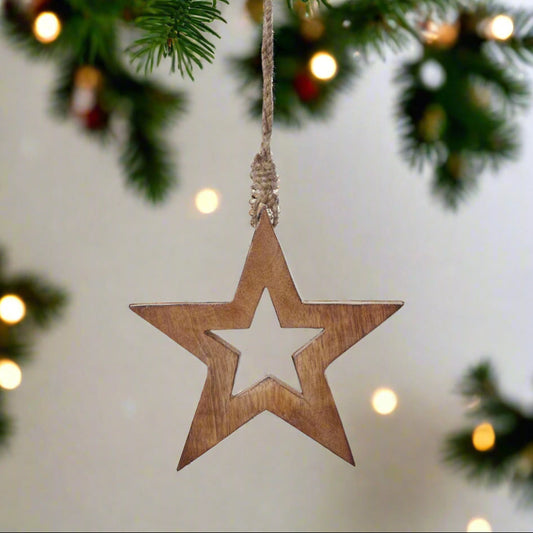 Wooden star ornament with cut out star middle hanging from a Christmas Tree.