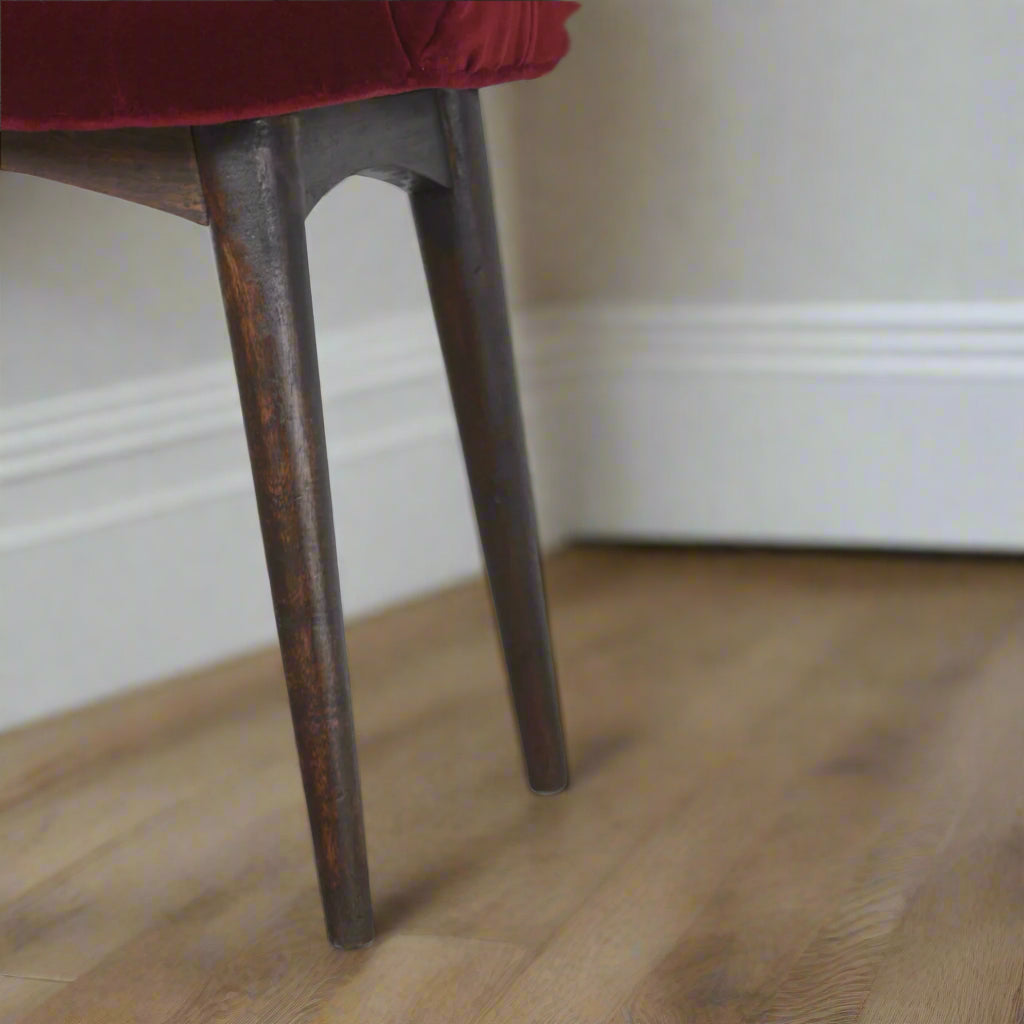 Close-up view of the solid mango wood Nordic style legs with a walnut finish on the Wine Red Velvet Curve Stool.