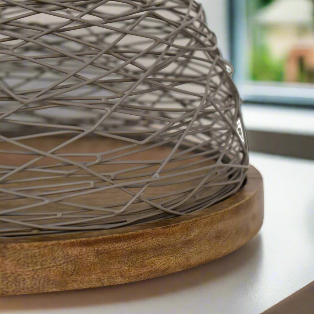Detailed shot of the Blue Bird Nest Cake Stand’s smooth wooden base and blue netted top craftsmanship